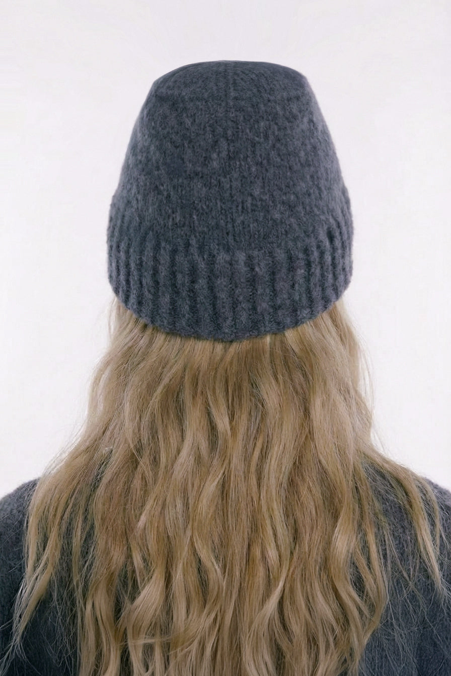 a female wearing a dark gray knit beanie with long blonde hair on a white background, Independent London designer travel Italian wool bucket hat.