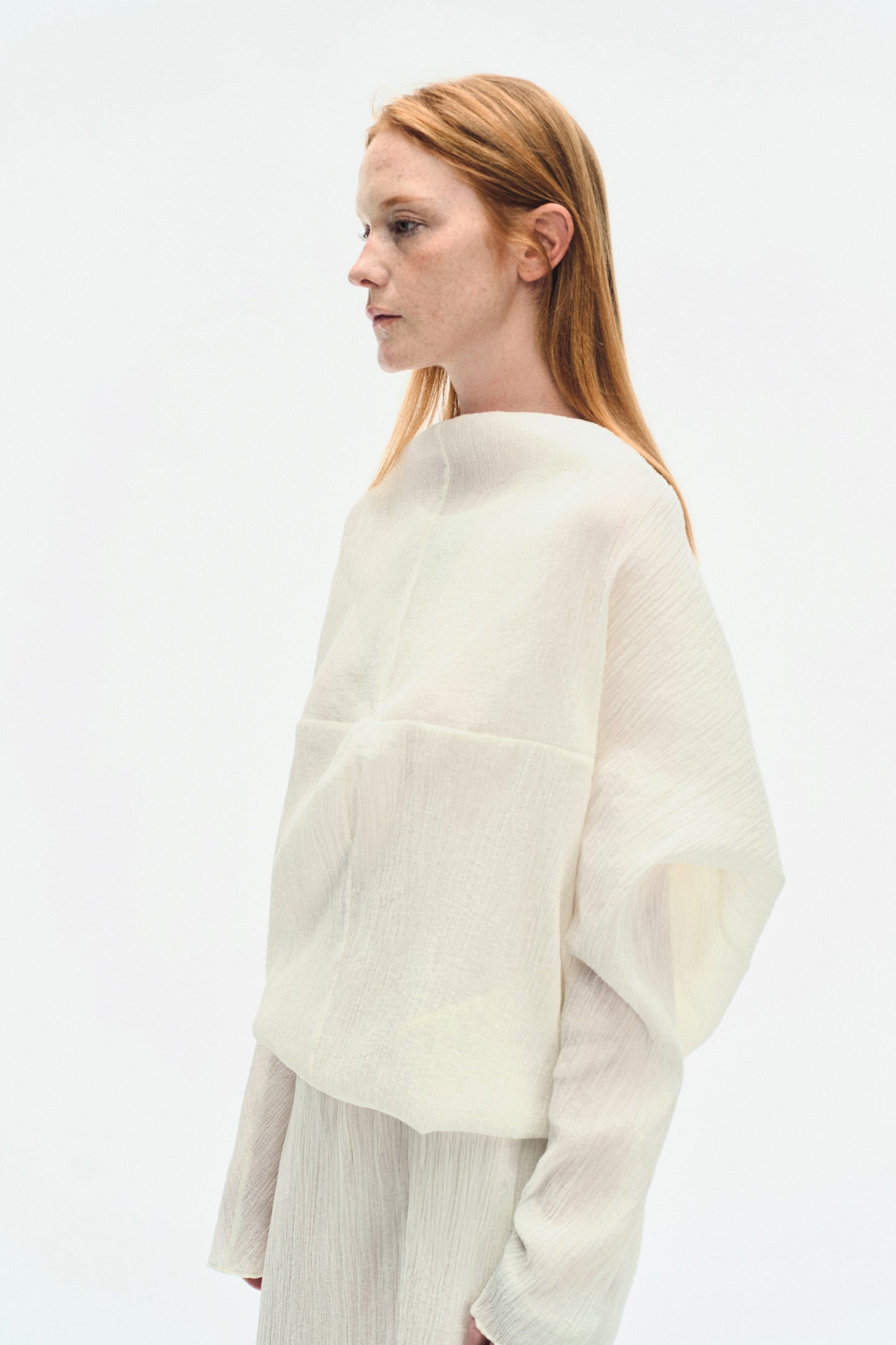 Close-up side portrait of model wearing the YIBRI White Wrinkle-Textured Reversible Top, highlighting the elegant neckline and airy wrinkle fabric.