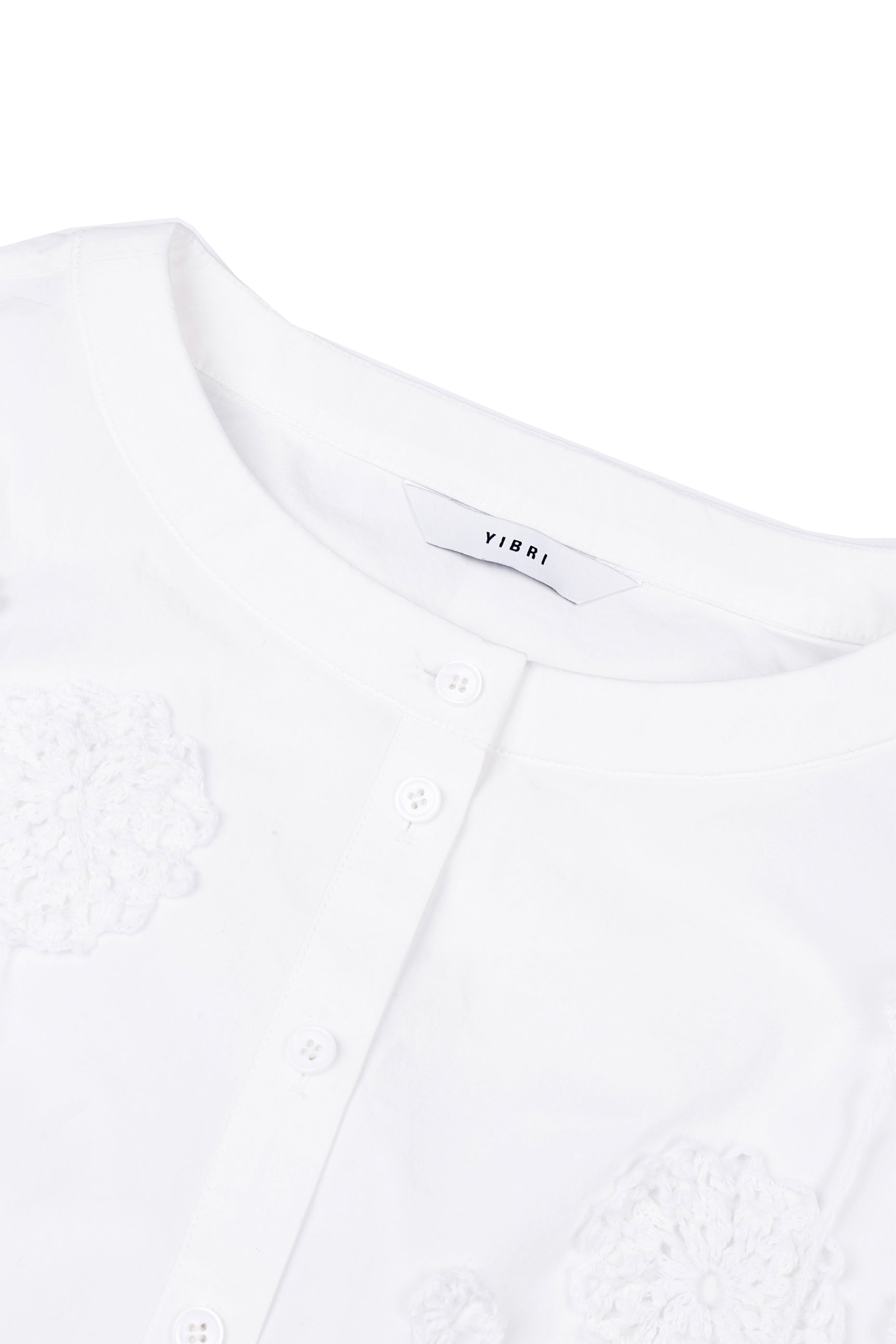 Close-up of the round neckline on the YIBRI cropped blouse, showing the crisp cotton poplin and refined buttoned placket.