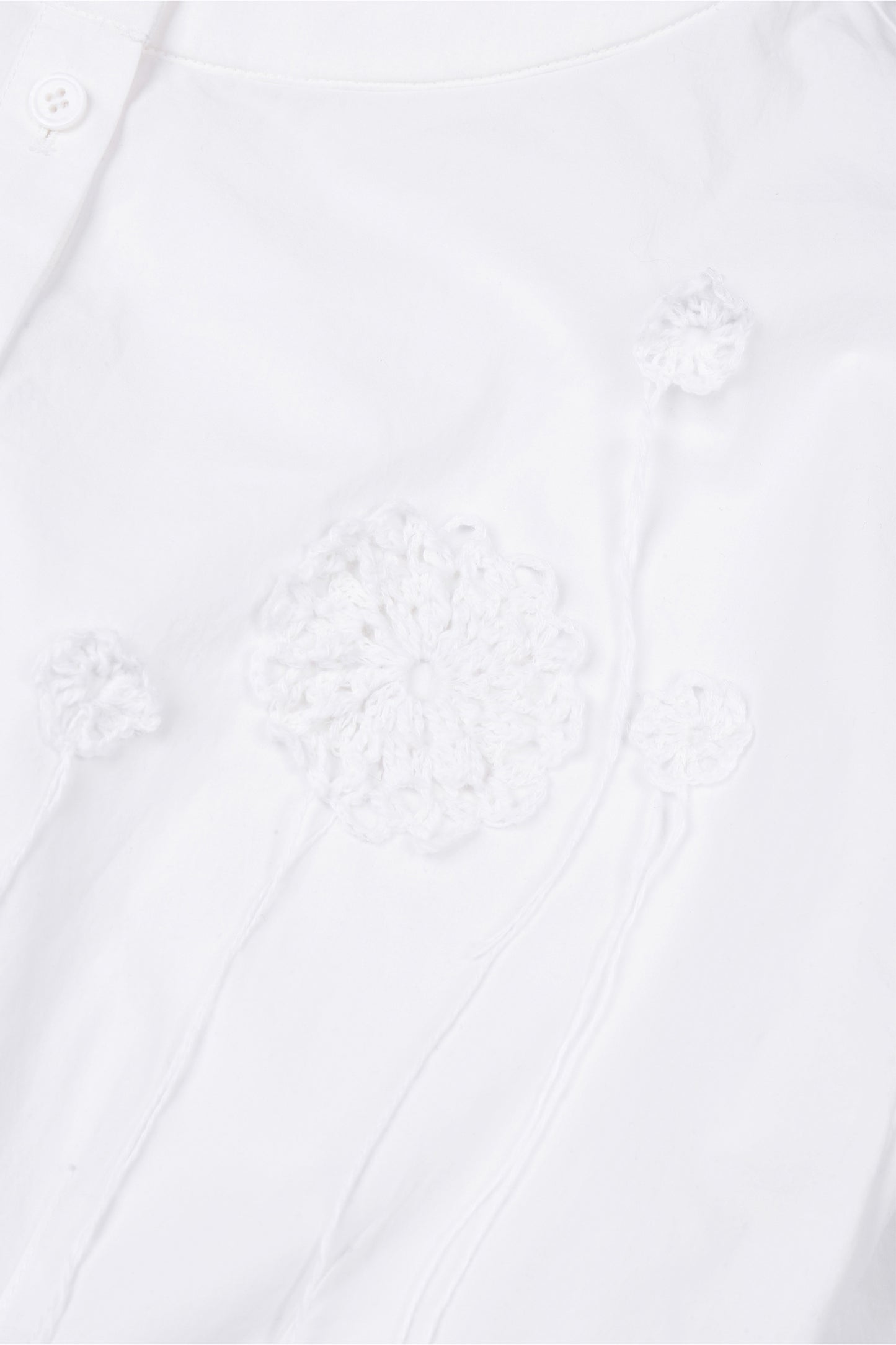 Detail view of the hand-crocheted flower appliqué on the YIBRI cropped blouse, highlighting the artisanal texture and delicate raised stitching.