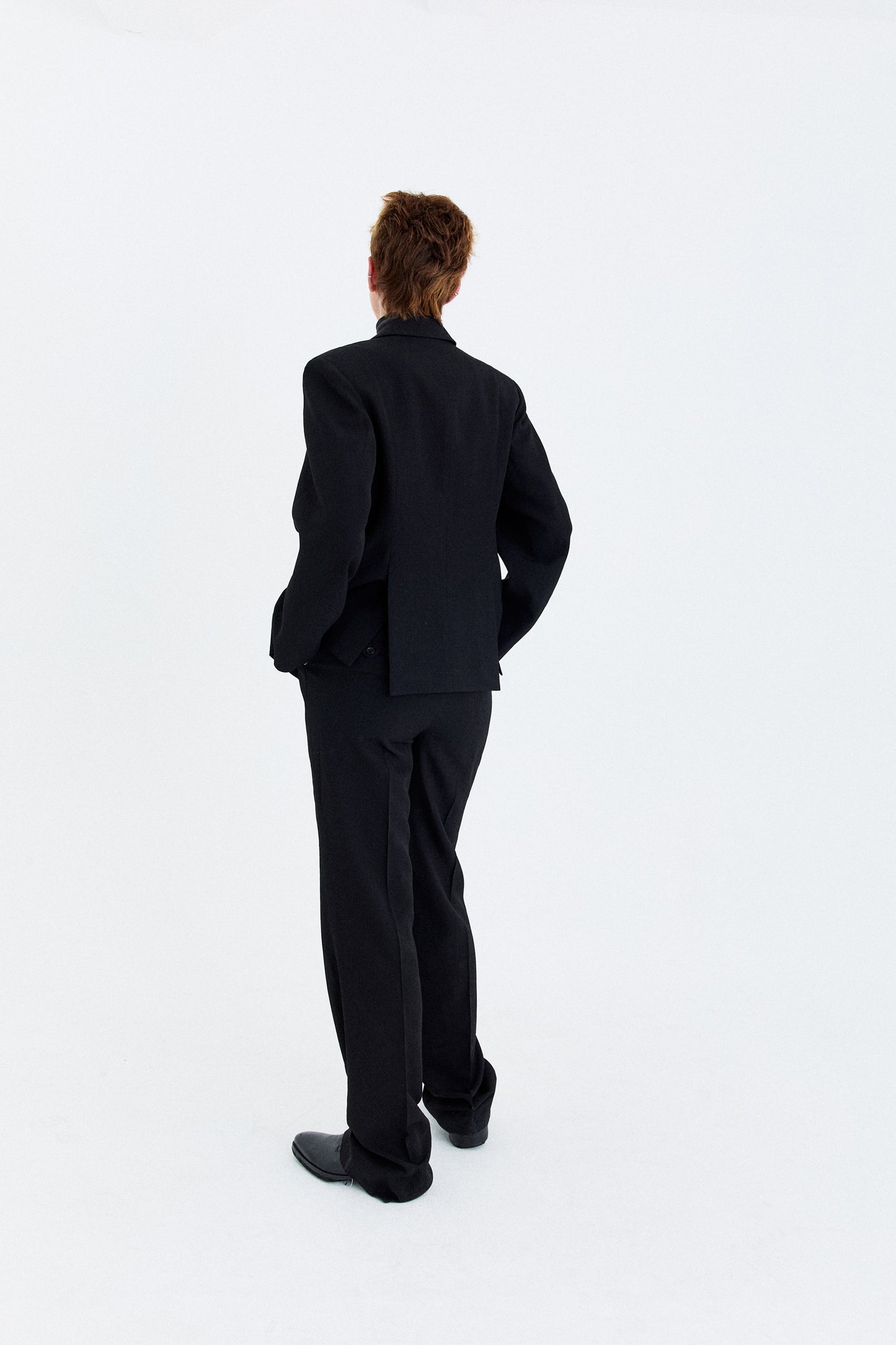 Back view of the model wearing the YIBRI double-breasted blazer, showing the sculpted back panels and smooth tailored drape.