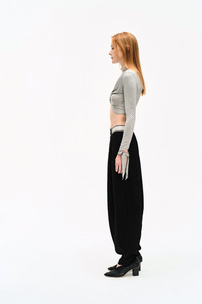 Side view of model in the YIBRI Grey Draped Jersey Crop Top, showing the fitted sleeves, tie ends and clean cropped side profile.