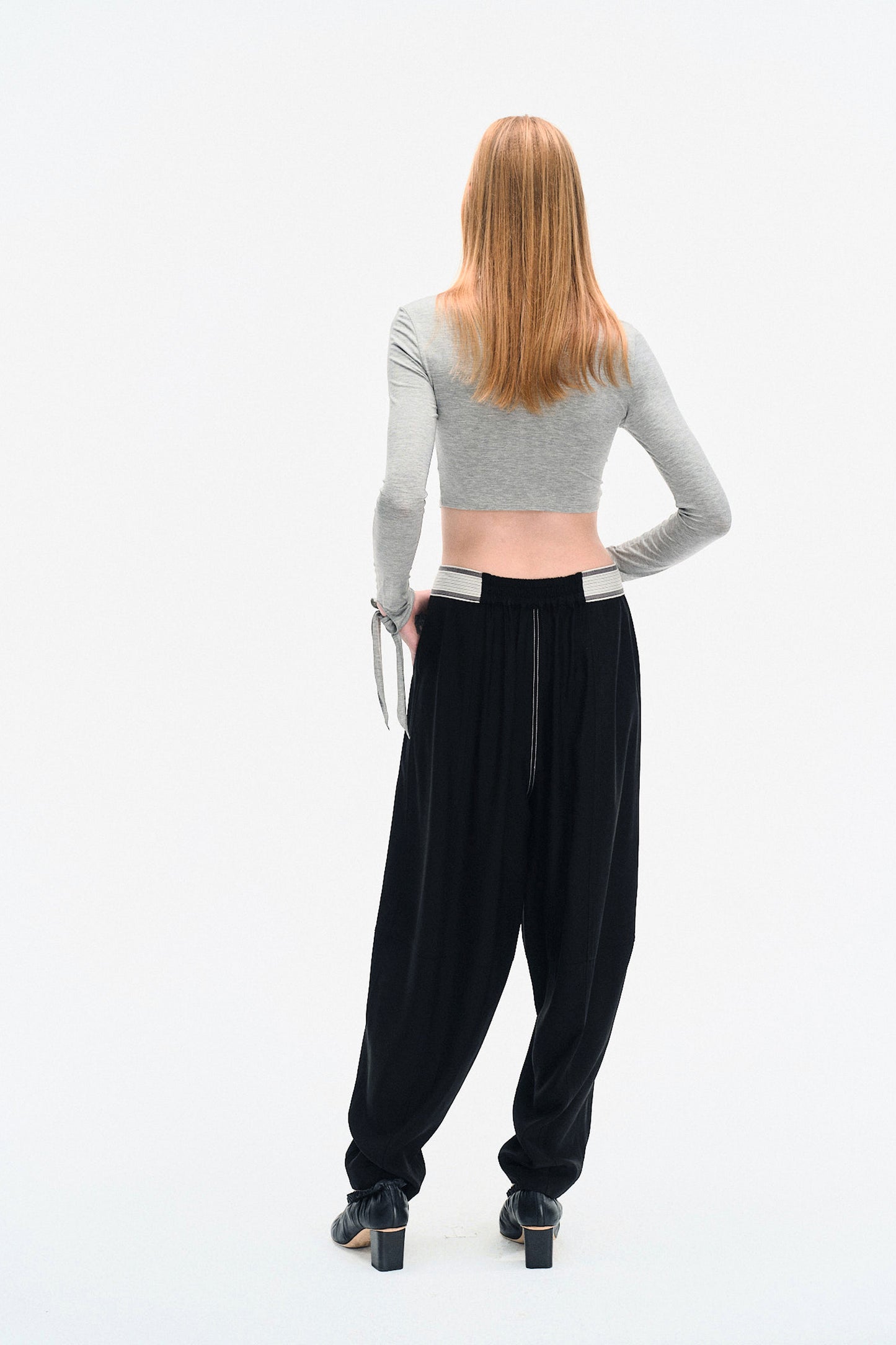 Back view of model wearing the YIBRI Grey Draped Jersey Crop Top, highlighting the minimal cropped back and long jersey sleeves.