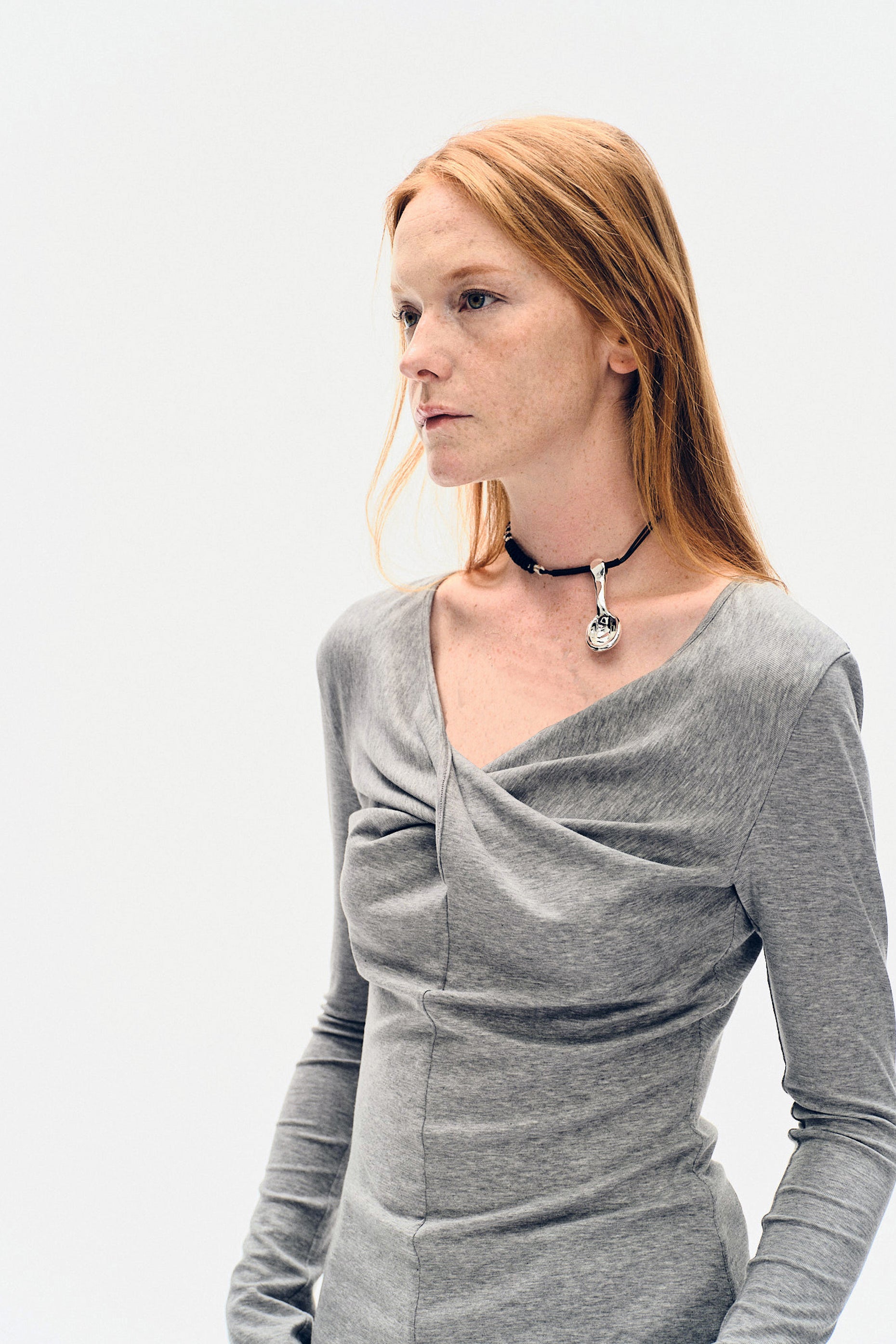 Portrait close-up of the YIBRI Grey Twisted Long Jersey Sleeve Top, showcasing the twisted neckline and soft draped jersey.