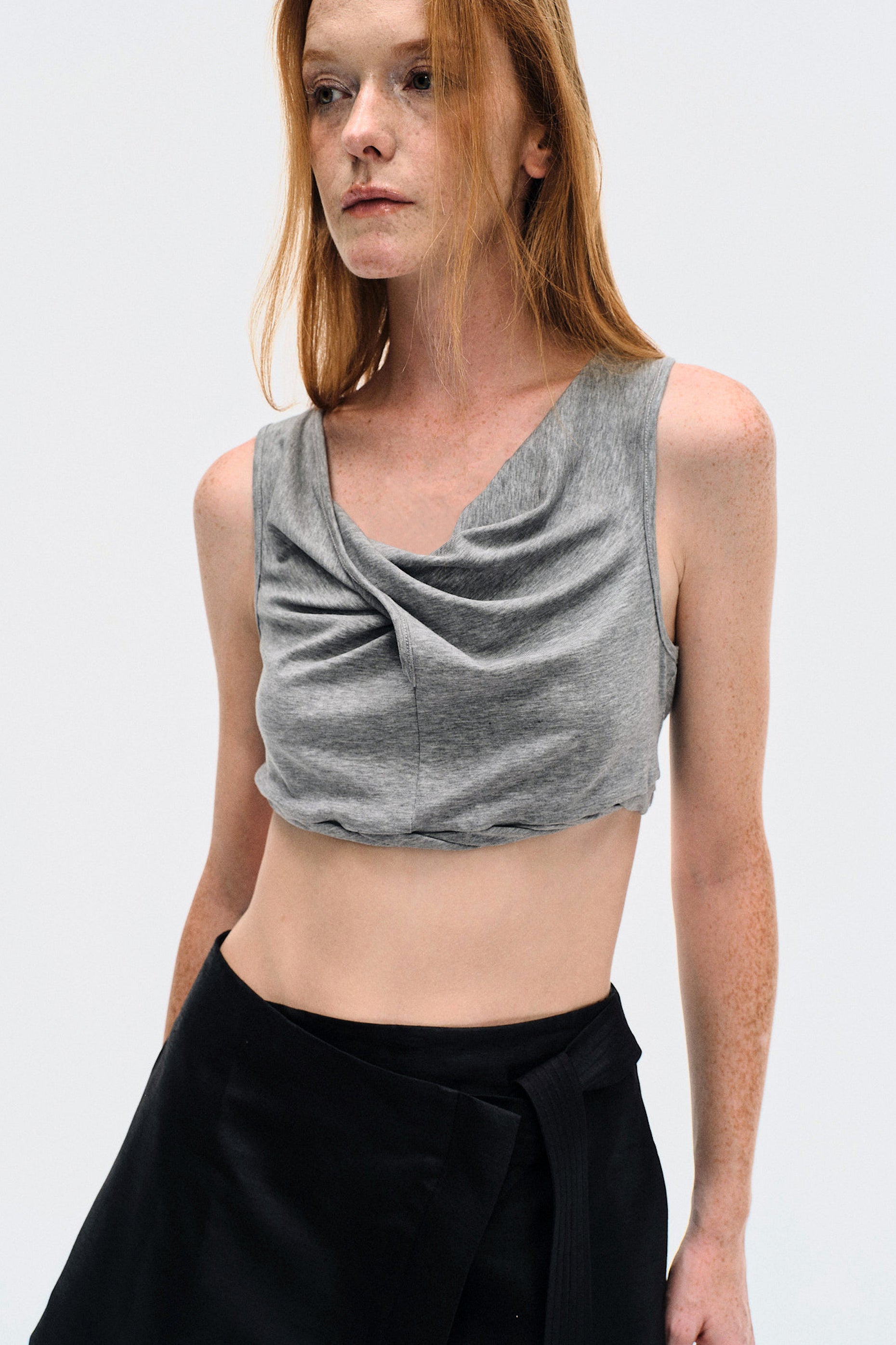 Close-up on model wearing the YIBRI Heather Grey Twisted Front Jersey Crop Top, focusing on the draped neckline and soft jersey texture.
