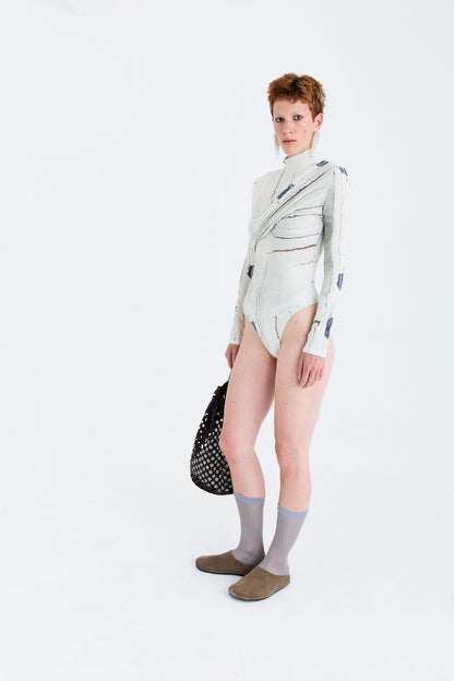 Model angled view wearing the YIBRI Printed Stretchy Open-Back Bodysuit, showing the long sleeves, marbled print and sculpted twist drape.