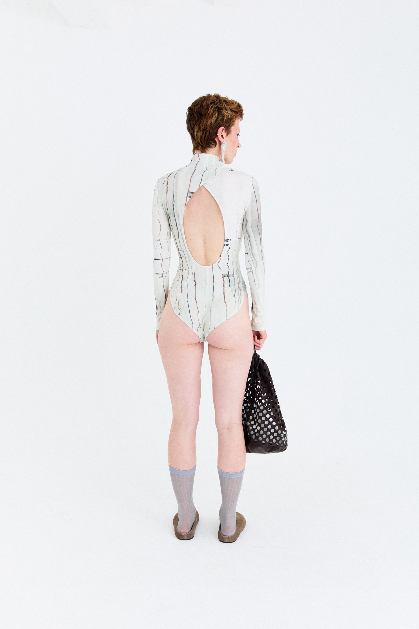 Back model view of the YIBRI Printed Stretchy Open-Back Bodysuit featuring the open oval cut-out and soft gathering at the twist seam.
