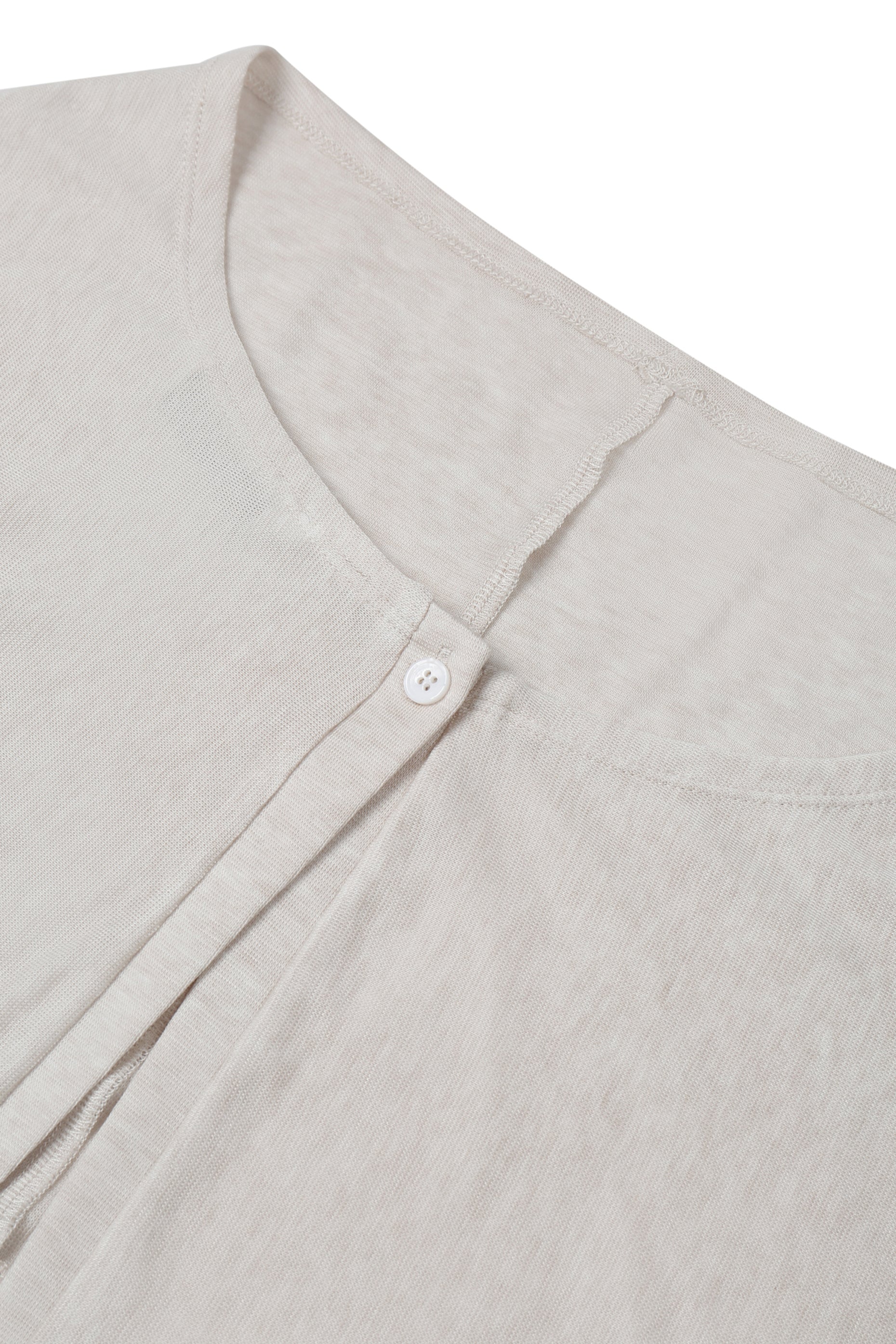 Close-up of the neckline and button fastening on the YIBRI Reversible Cropped Cardigan, showing the fine textured jersey and subtle top stitching.