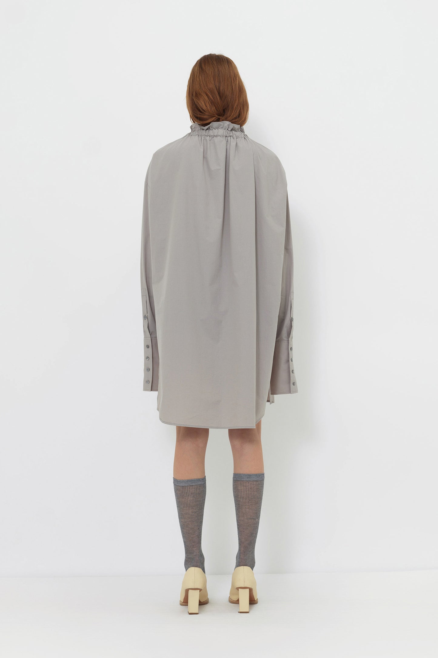 Back angle of model wearing YIBRI Ruched Collar Long Shirt showing soft fabric movement, gathered neckline and minimalist long silhouette.