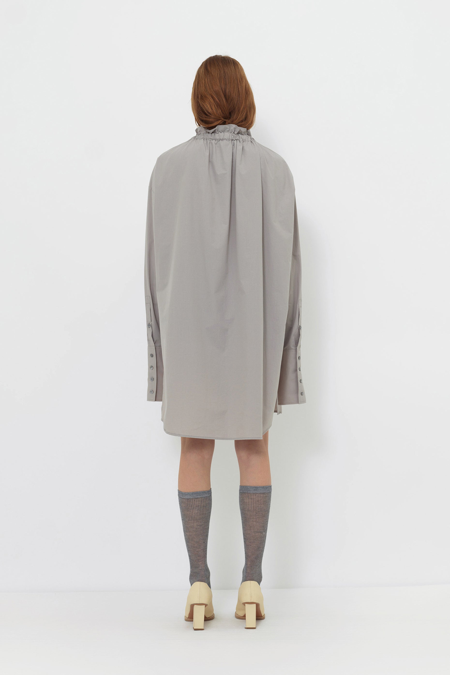 Back angle of model wearing YIBRI Ruched Collar Long Shirt showing soft fabric movement, gathered neckline and minimalist long silhouette.