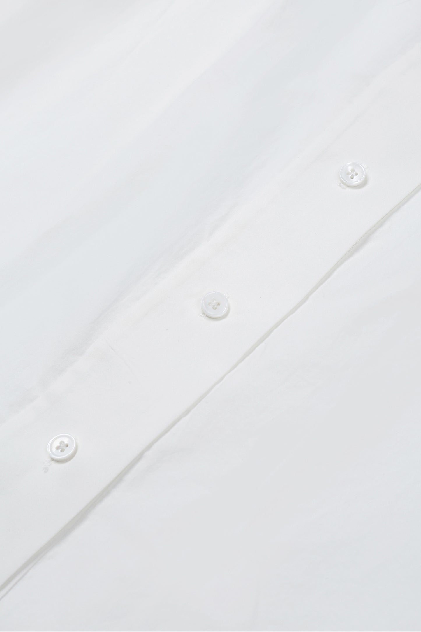 Close-up of white washed cotton fabric and button details on the YIBRI Ruched Collar Long Shirt, highlighting natural fibre texture and refined craftsmanship.