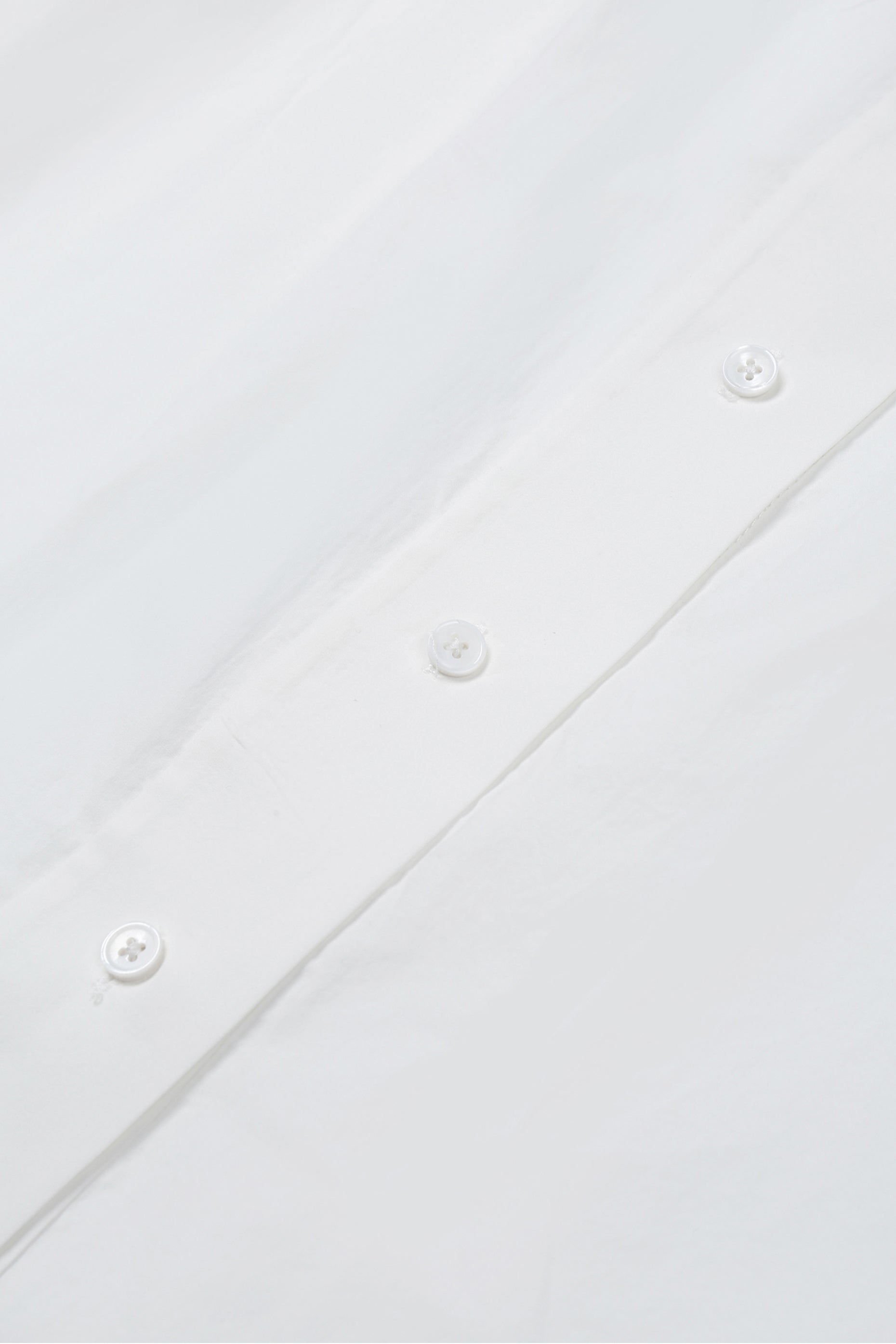 Close-up of white washed cotton fabric and button details on the YIBRI Ruched Collar Long Shirt, highlighting natural fibre texture and refined craftsmanship.