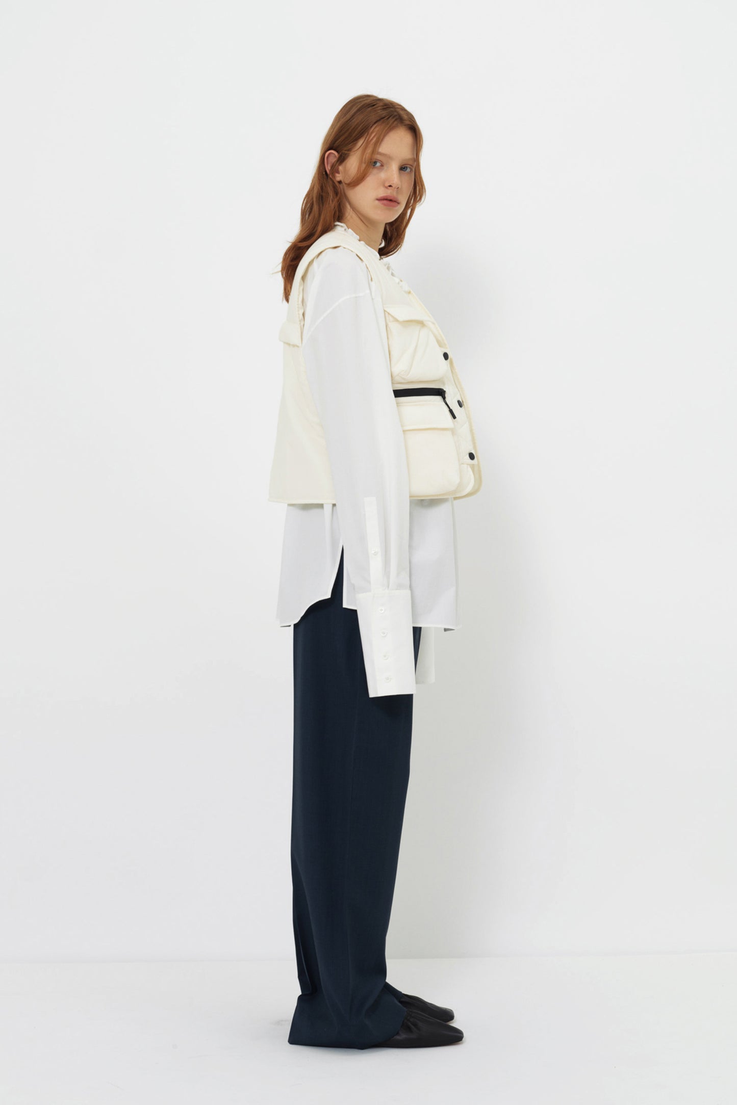 Side view of model in the YIBRI Ruched Collar Short Shirt in white washed cotton, showing extended hem, clean drape and gathered neckline.