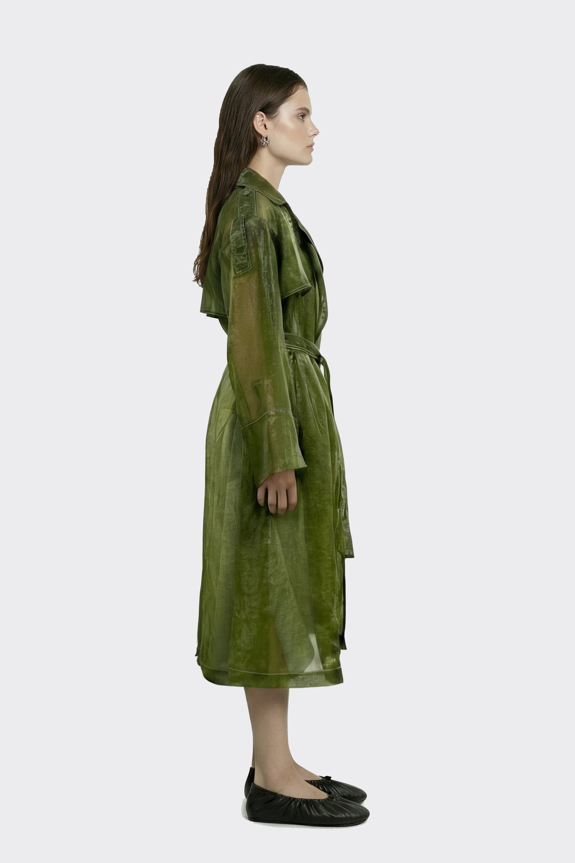 Woman wearing a green sheer trench against a white background