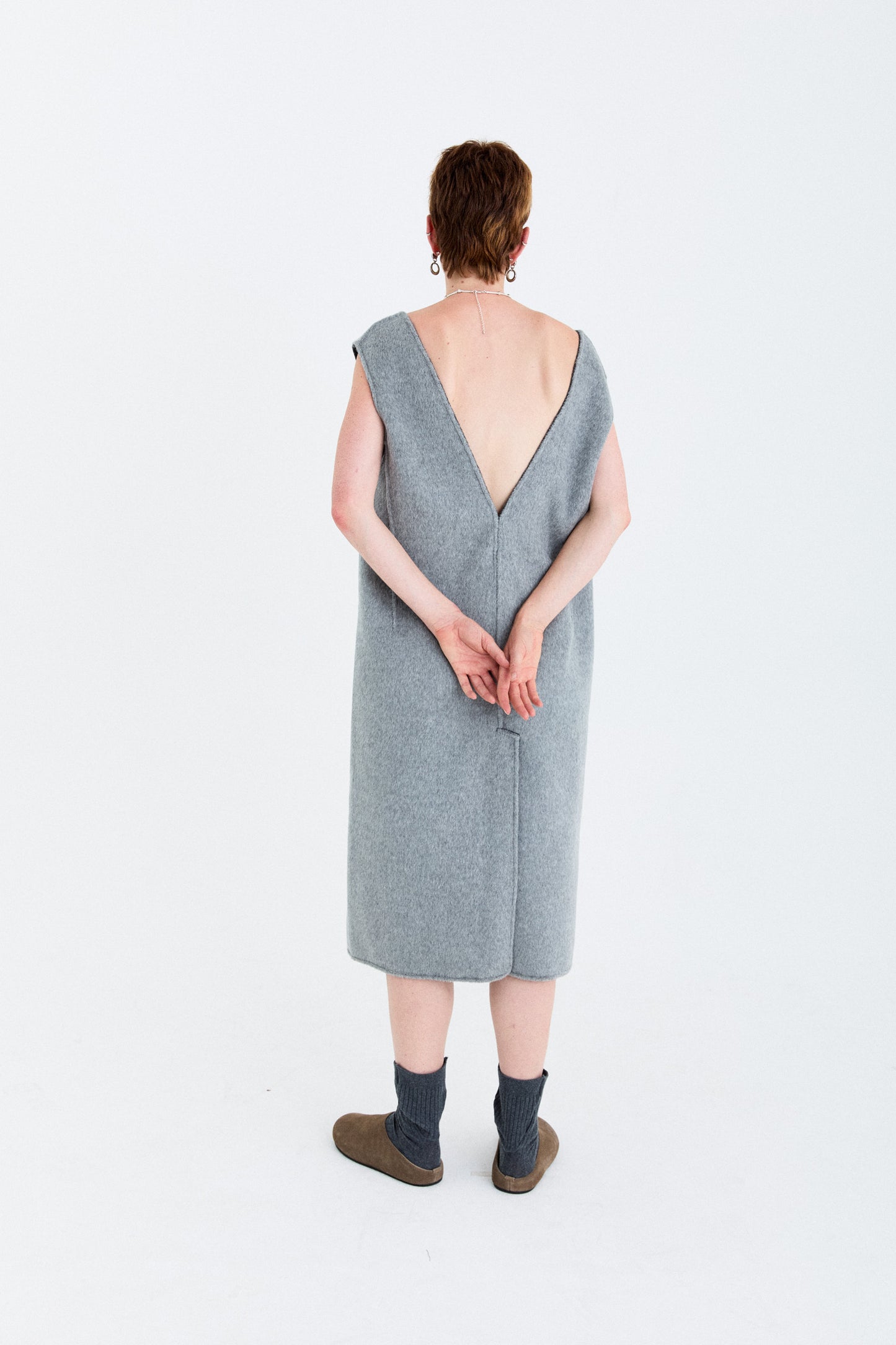 Person wearing a gray sleeveless dress with a V-neckline on a white background, the fabric is made of long hair double  face bi-colour wool