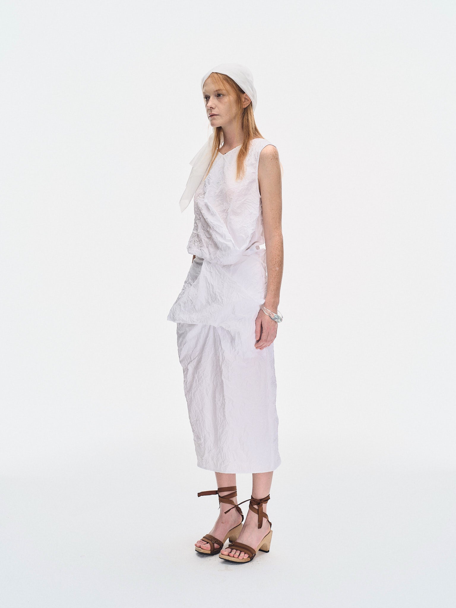 Three-quarter view of the YIBRI White Crinkled Texture Sleeveless Top on model, highlighting the asymmetrical draped panel and airy crushed cotton.