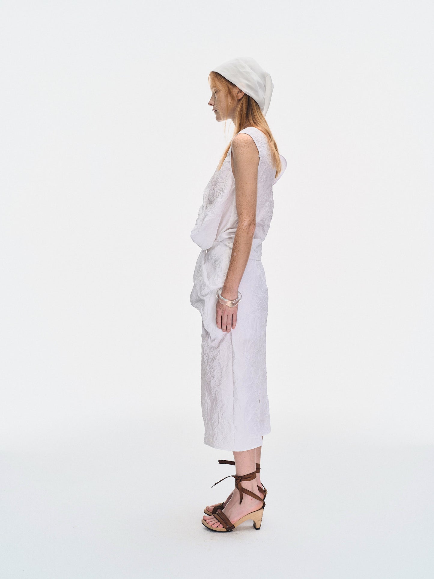 Side view of the YIBRI White Crinkled Texture Sleeveless Top showing the sculptural folded volume and modern sleeveless silhouette.