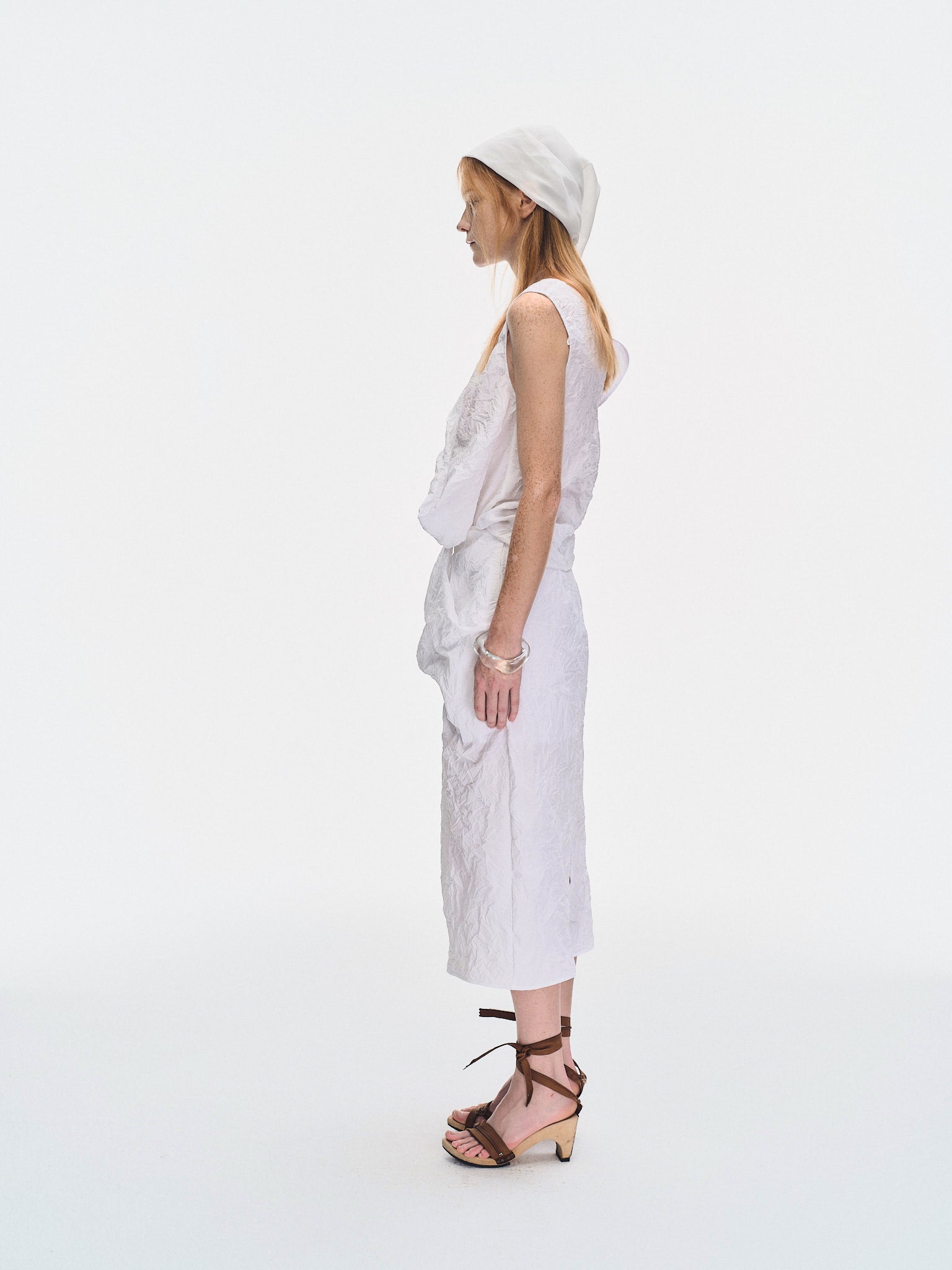 Side view of the YIBRI White Crinkled Texture Sleeveless Top showing the sculptural folded volume and modern sleeveless silhouette.