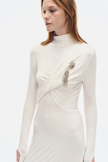 Front close-up of YIBRI ivory draped high-neck dress featuring delicate wrap detail and textured silver brooch embellishment.