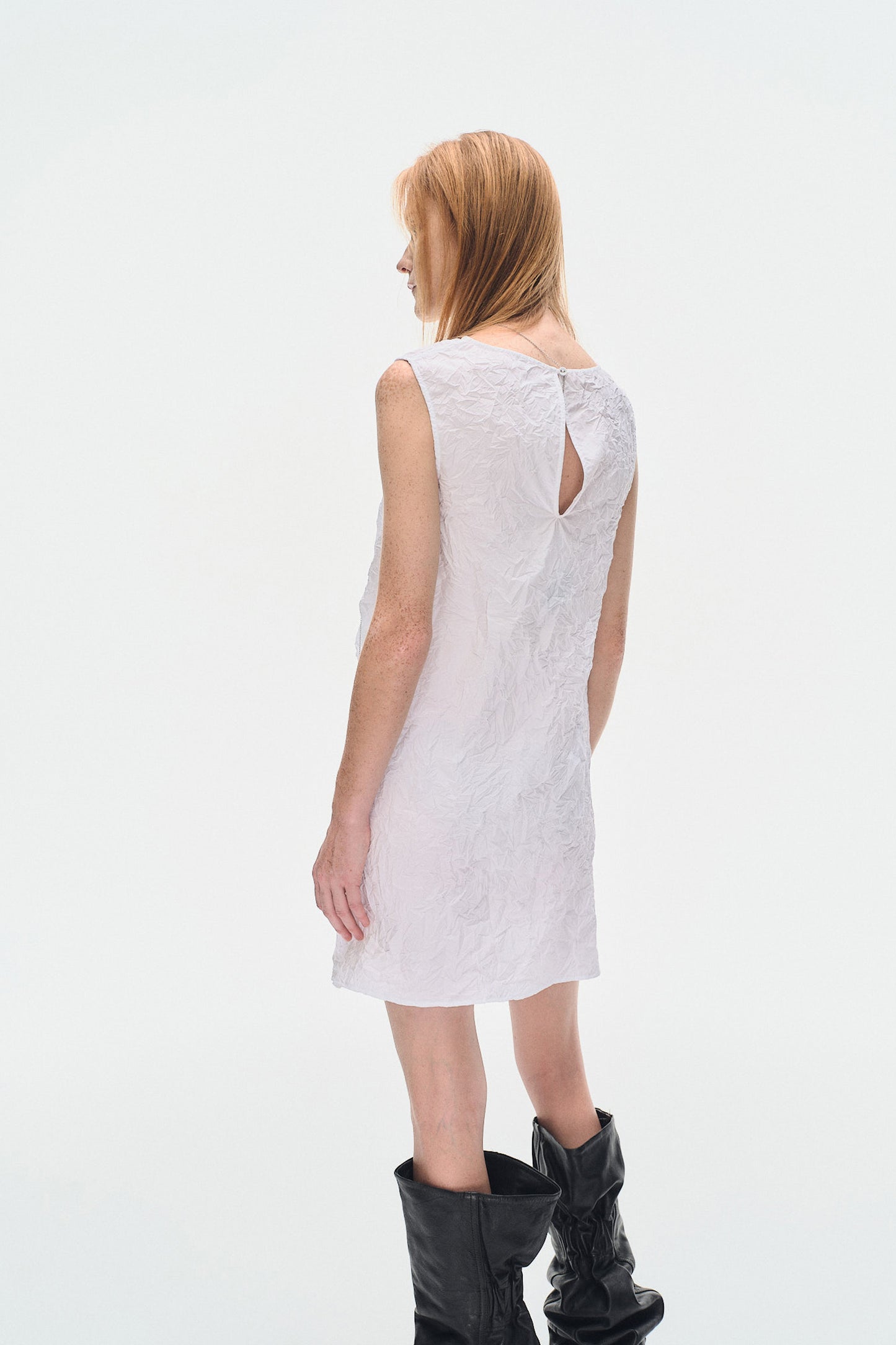 Side view of model wearing YIBRI White Sculpted Crinkle Mini Dress highlighting sculptural draped volume and textured crinkle fabric