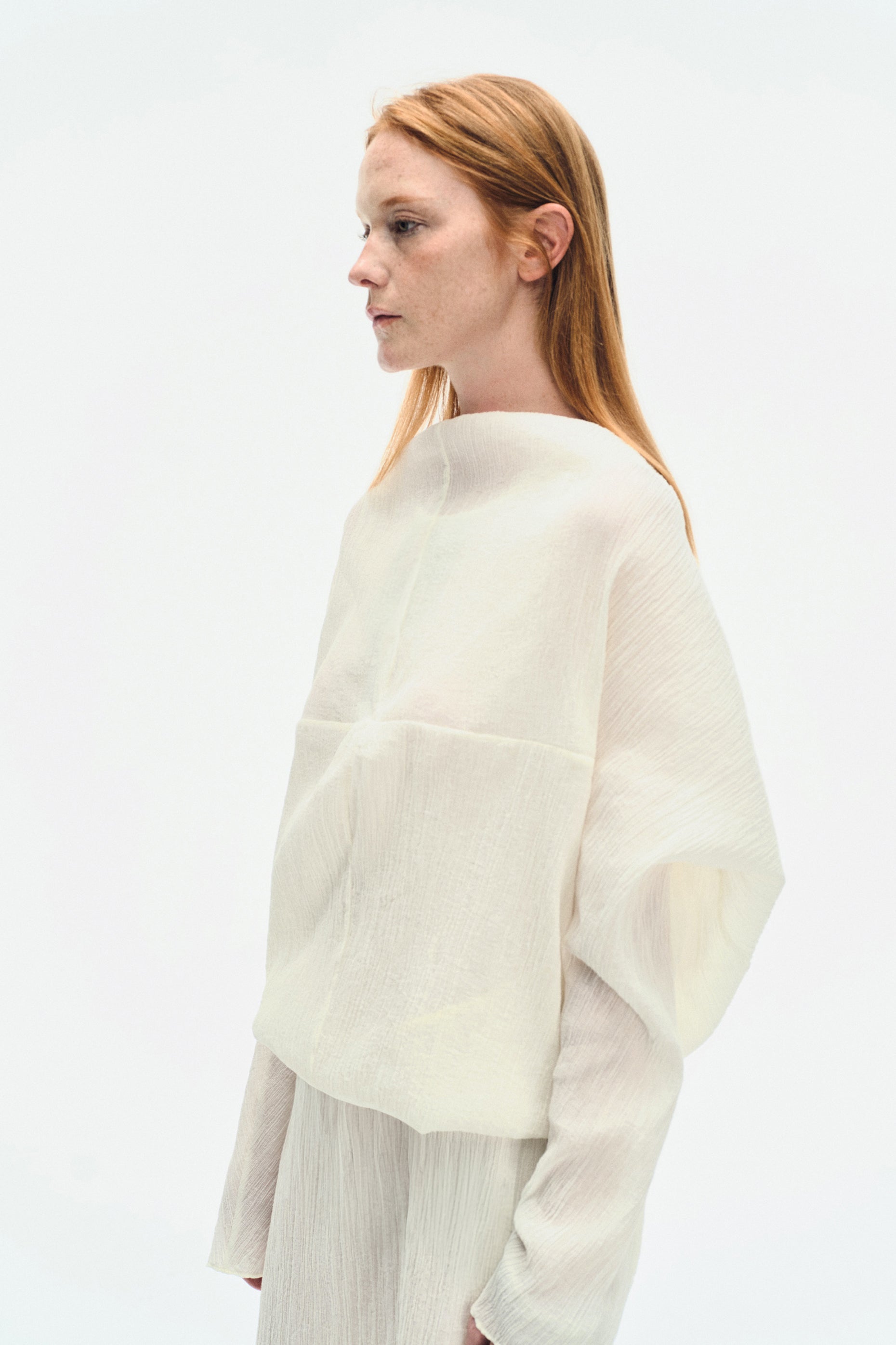 Close-up side portrait of model wearing the YIBRI White Wrinkle-Textured Reversible Top, highlighting the elegant neckline and airy wrinkle fabric.