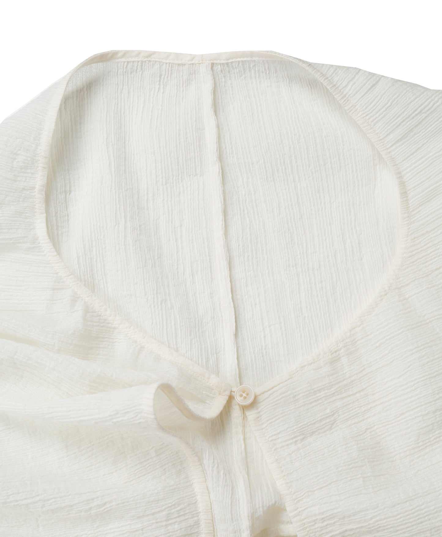 Detail of the neckline and small button closure on the YIBRI White Wrinkle-Textured Reversible Top, showing delicate edges and fine finishing.