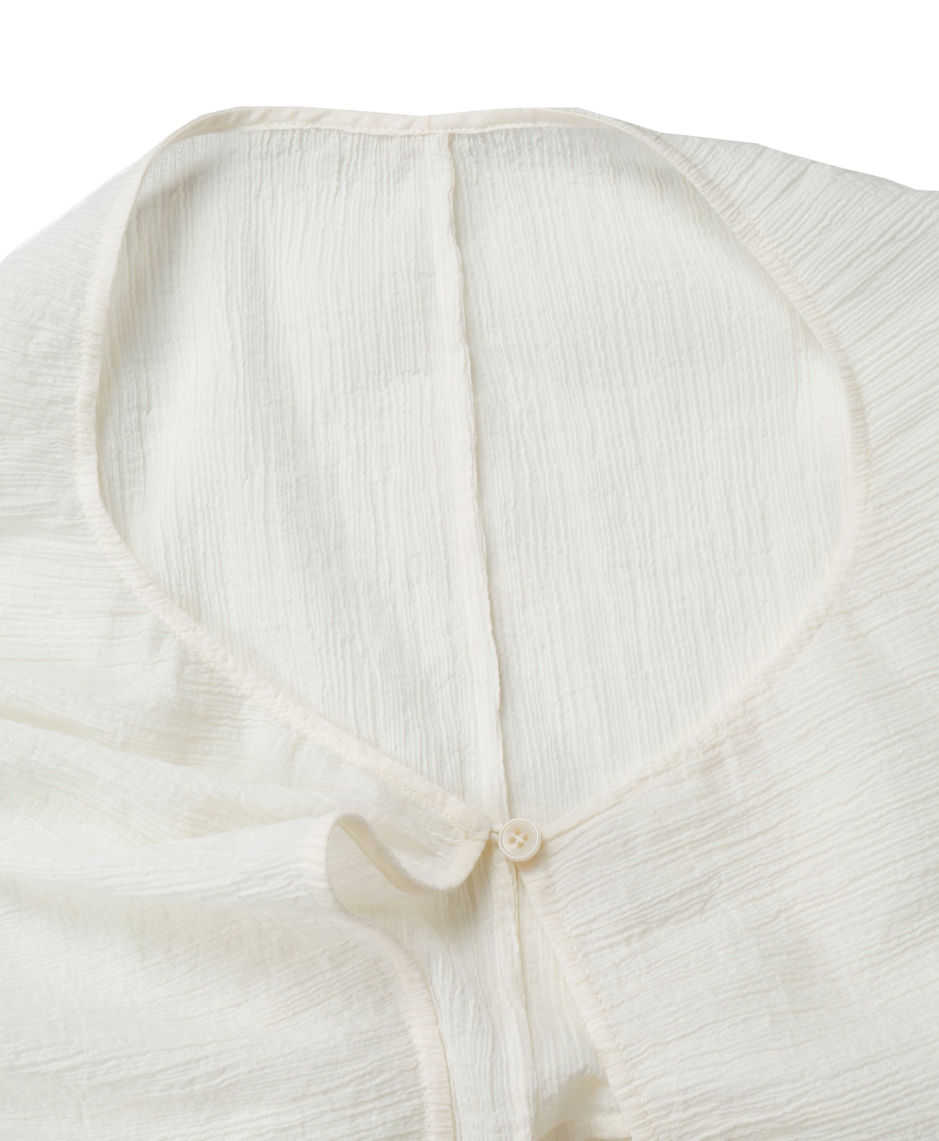 Detail of the neckline and small button closure on the YIBRI White Wrinkle-Textured Reversible Top, showing delicate edges and fine finishing.