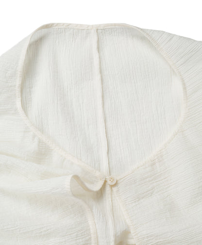 Detail of the neckline and small button closure on the YIBRI White Wrinkle-Textured Reversible Top, showing delicate edges and fine finishing.