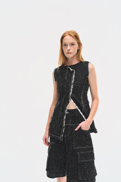 Woman wearing a black sleeveless dress with cut-out design on a white background