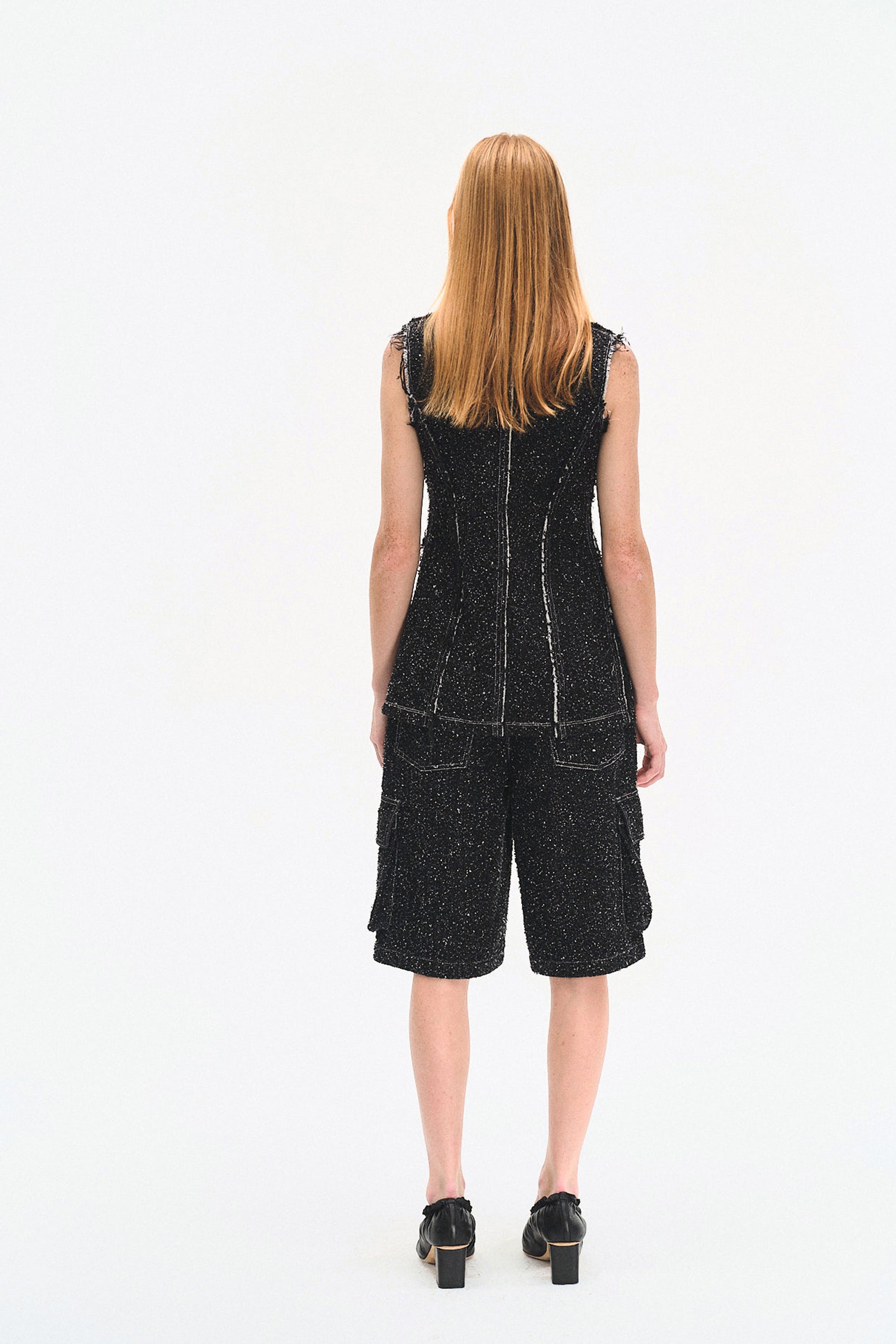 Person wearing a black sleeveless dress with a white background