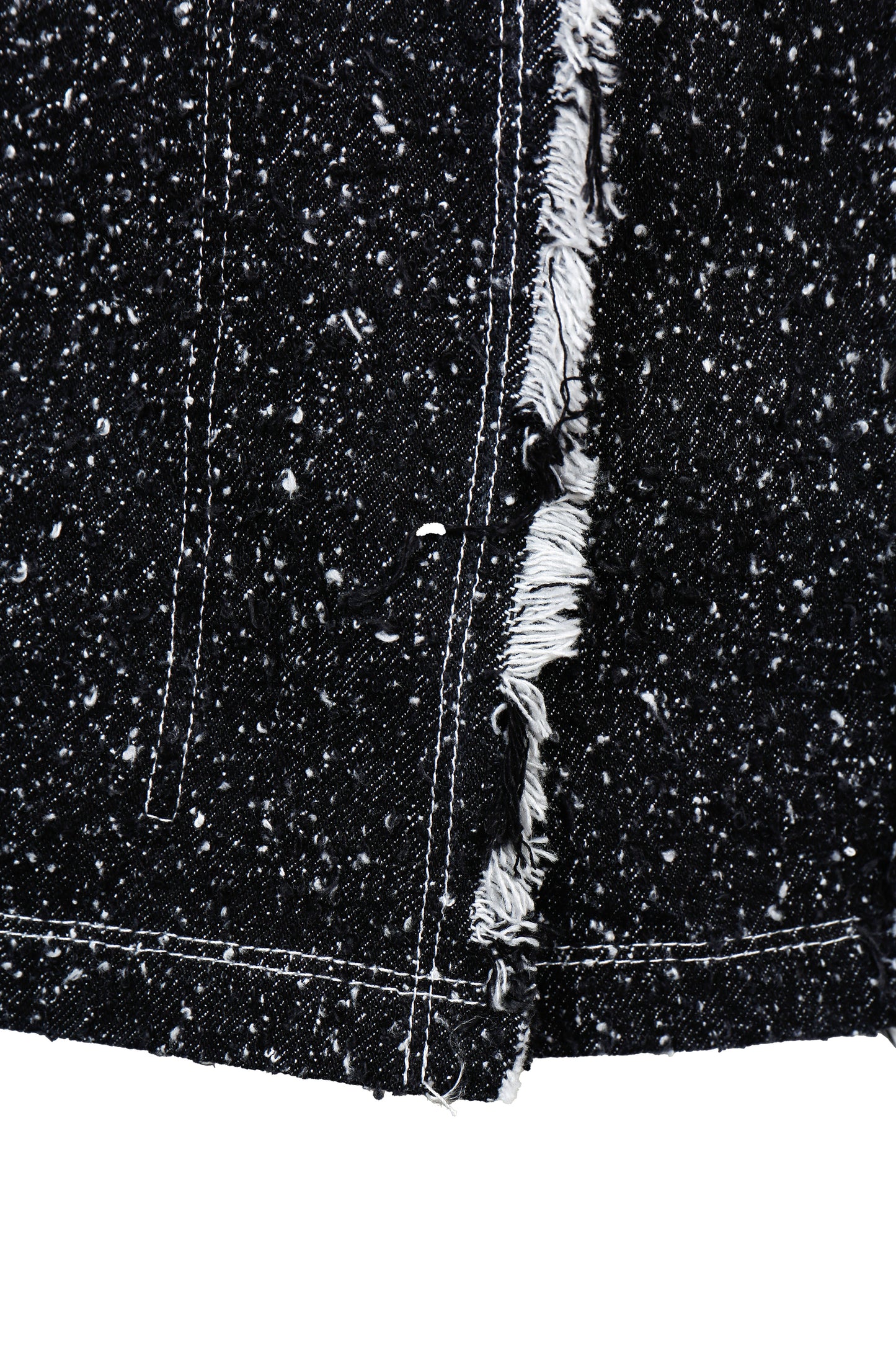 Close-up of a black denim fabric with frayed edge on a white background