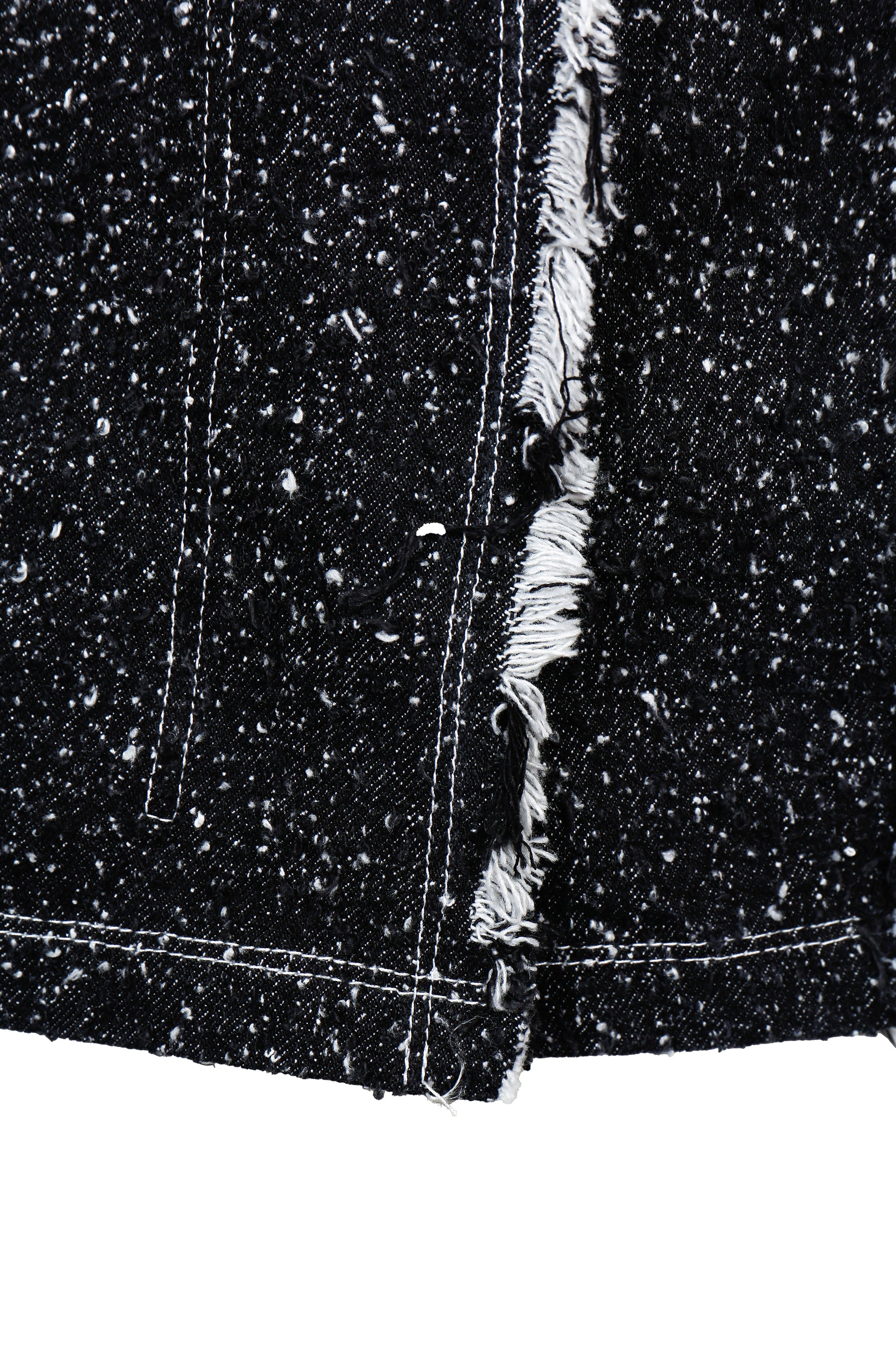 Close-up of a black denim fabric with frayed edge on a white background