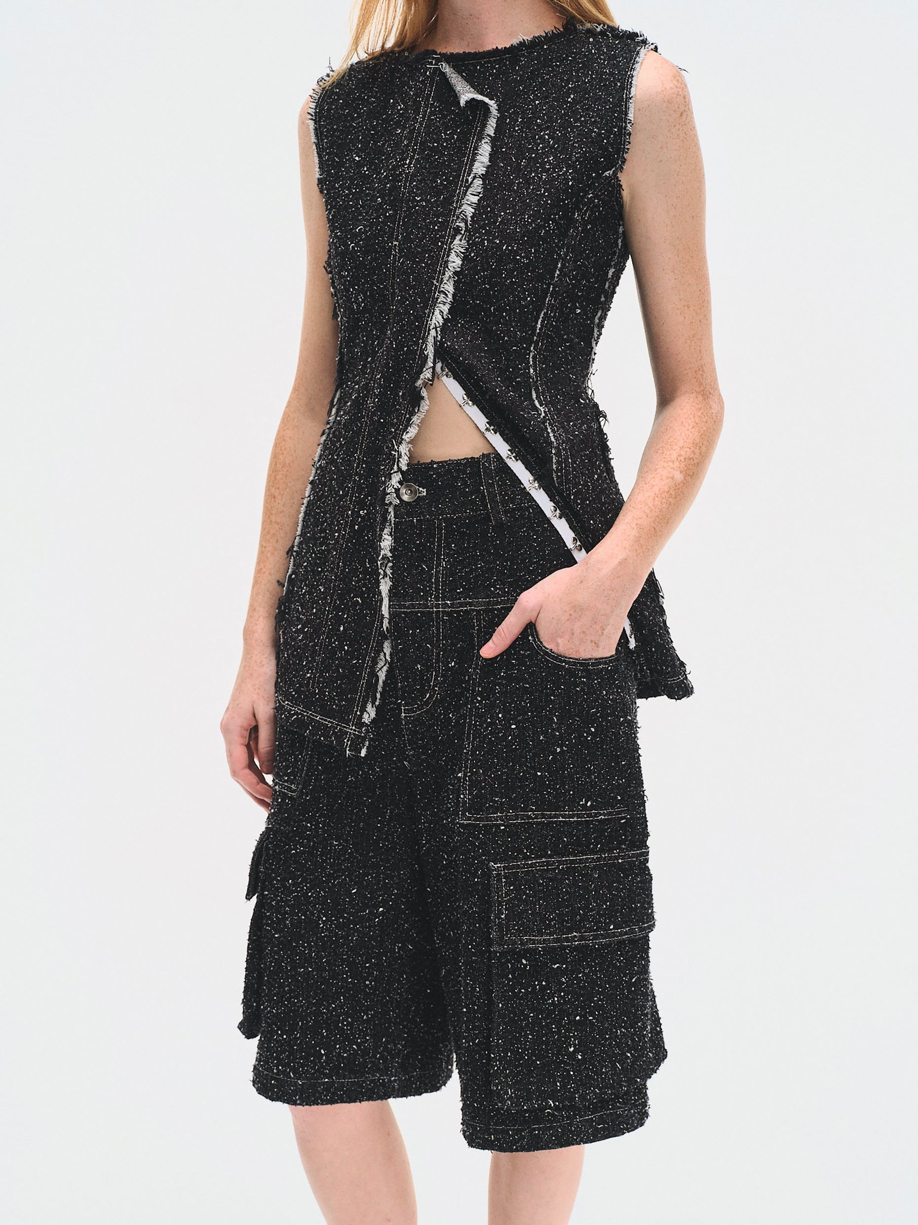 Person wearing a black textured sleeveless top and high-waisted shorts on a white background