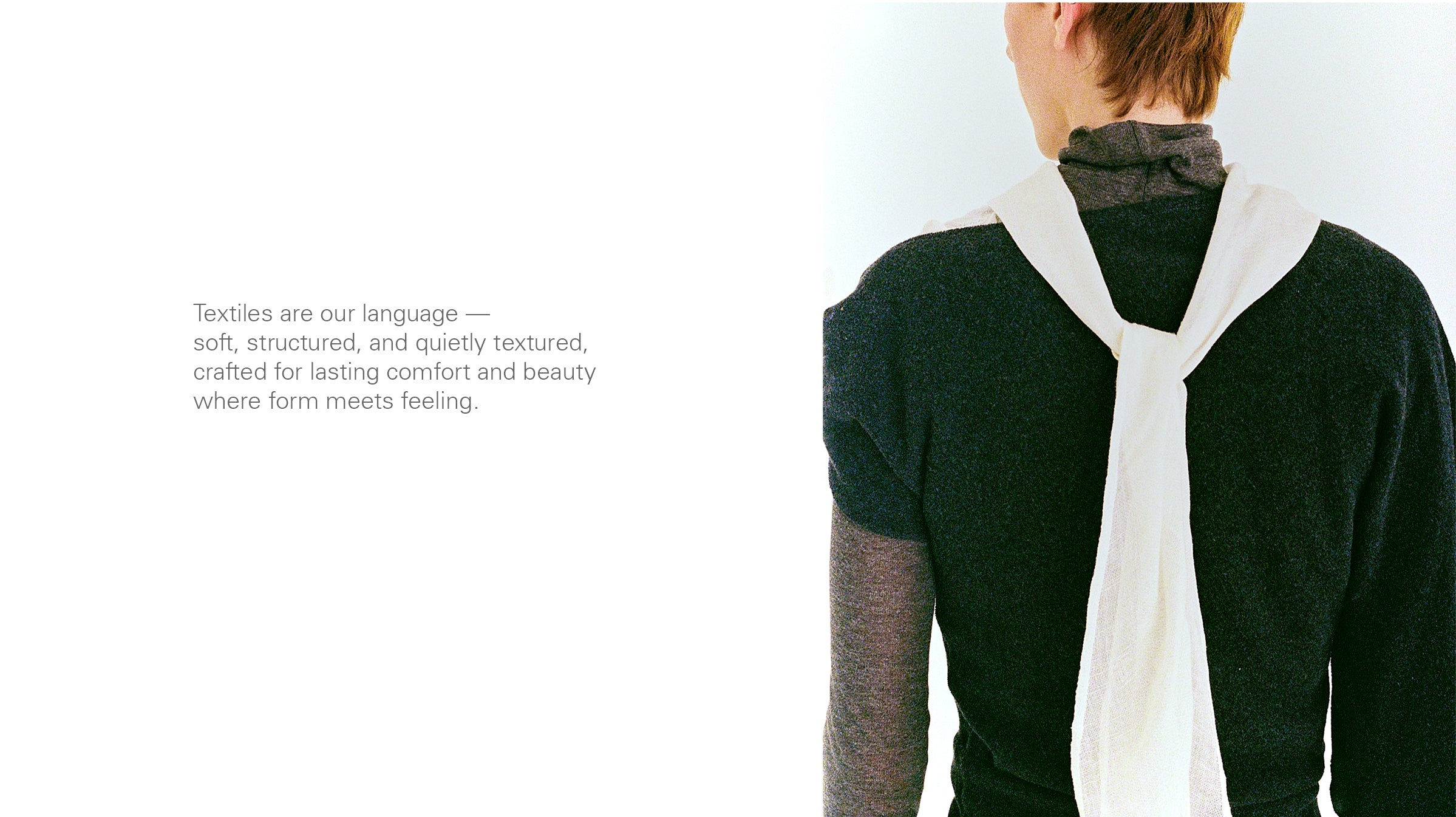 Person wearing a dark asymmetric flannel sweater with a white scarf draped over their shoulders on a plain background. grey sheer knitted turtle neck jersey top 